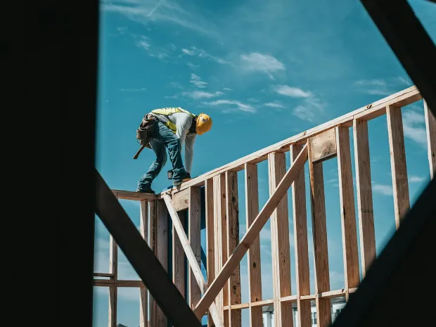 A framer at work on top of a wood-framed wall