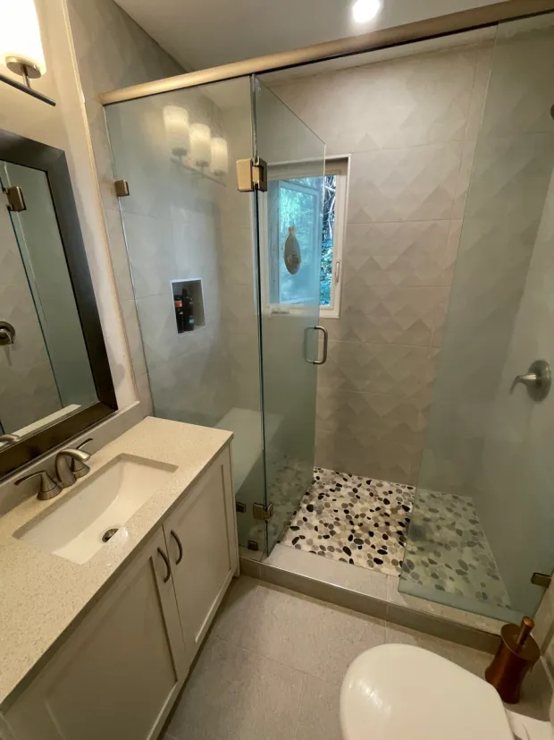 Glass shower with hexagon wall tile and a pebble floor, built by DreamPro Contracting