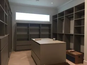 Built-in storage room with open shelving and a central island, by DreamPro Contracting