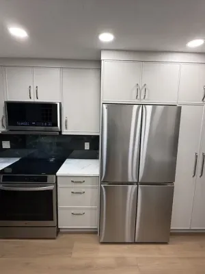Finished kitchen with white cabinetry, quartz counters, and a black backsplash in Langley, by DreamPro Contracting