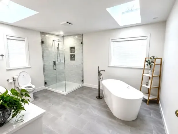 Finished bathroom with a walk-in glass shower, a freestanding tub, and a skylight, built by DreamPro Contracting