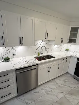 Finished kitchen with white shaker cabinets, a marble-look backsplash, and black hardware