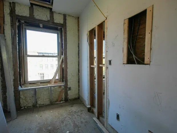 A wall opened to the framing around a window, mid-repair